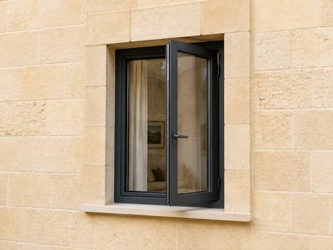 Illustrative anthracite casement window with an open sash and visible handle in a limestone wall.