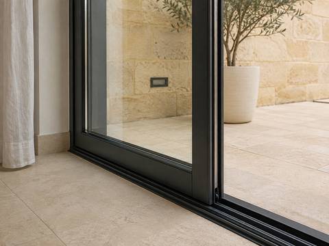 Illustrative open aluminium sliding door showing the track and terrace threshold.